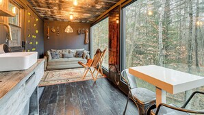 Un intérieur moderne avec un plafond en bois, un canapé, une table à manger et une grande fenêtre donnant sur une forêt.