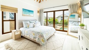 A bedroom with a large bed, a nightstand, a dresser, and a view of the outdoors through large windows.