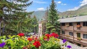 A hotel with a mountain view, surrounded by lush greenery and tall trees. - Family friendly 2-bedroom condo in Vail perfect for your year-round getaway (Vail)