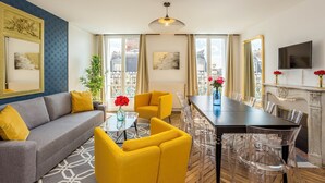 Ein modernes Wohnzimmer mit einer Couch, gelben Sesseln, einem Esstisch und einem Kamin.