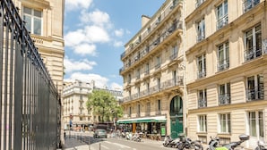 Straßenansicht mit einem Café, abgestellten Rollern und klassischer europäischer Architektur.