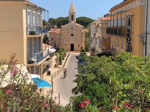 A street view with a church, buildings, and a cyclist. - The Little Arbanais : Ideal studio near the sea (Hyères)