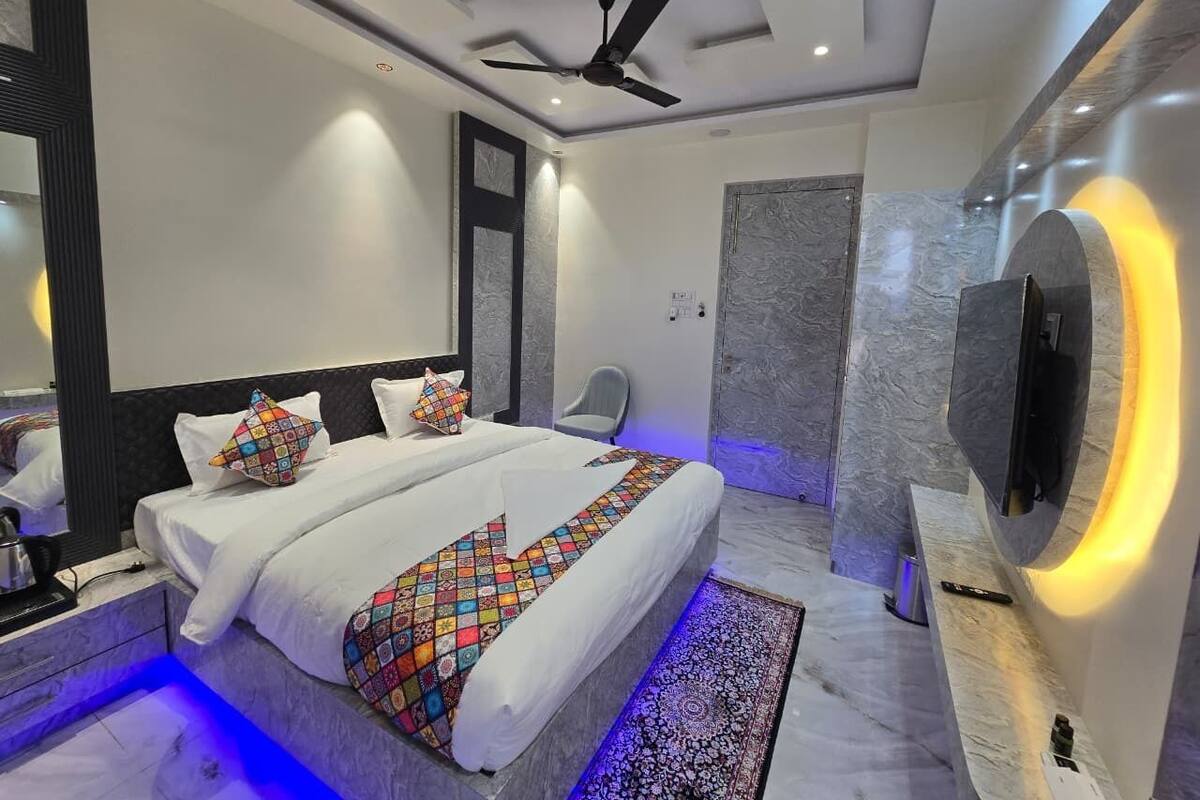 Ein modernes Hotelzimmer mit einem großen Bett, einem Deckenventilator und einem flachbildfernseher an der Wand.