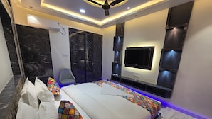 Un dormitorio moderno con una cama grande, un televisor montado en la pared y un ventilador de techo.