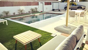 A backyard with a swimming pool, a covered patio area, and outdoor furniture. - Casa Alegria (Tunes)