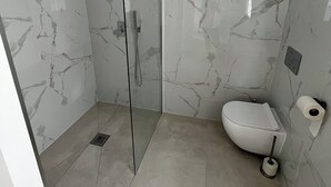 A bathroom with a glass shower enclosure, a toilet, and a bidet. - Casa Alegria (Tunes)