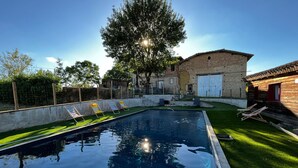 A swimming pool with clear water, surrounded by a grassy area and a stone building. - Large family home with swimming pool ideal for holidays with friends or family (Sérignac)