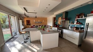 A modern kitchen with a central island, stainless steel appliances, and a view of the outdoors. - Large family home with swimming pool ideal for holidays with friends or family (Sérignac)