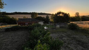 A rural landscape with a wooden cabin, open fields, and a sunset in the background. - Large family home with swimming pool ideal for holidays with friends or family (Sérignac)