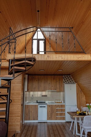 Een houten interieur met een keuken, eethoek en een spiltrap.