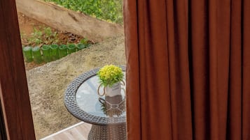 A patio area with a round table and two chairs, a small potted plant, and a view of a green lawn and a wooden deck.