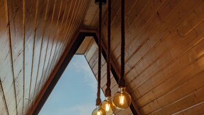 Una habitación con techo inclinado, vigas de madera y vistas a un paisaje con árboles y edificios.