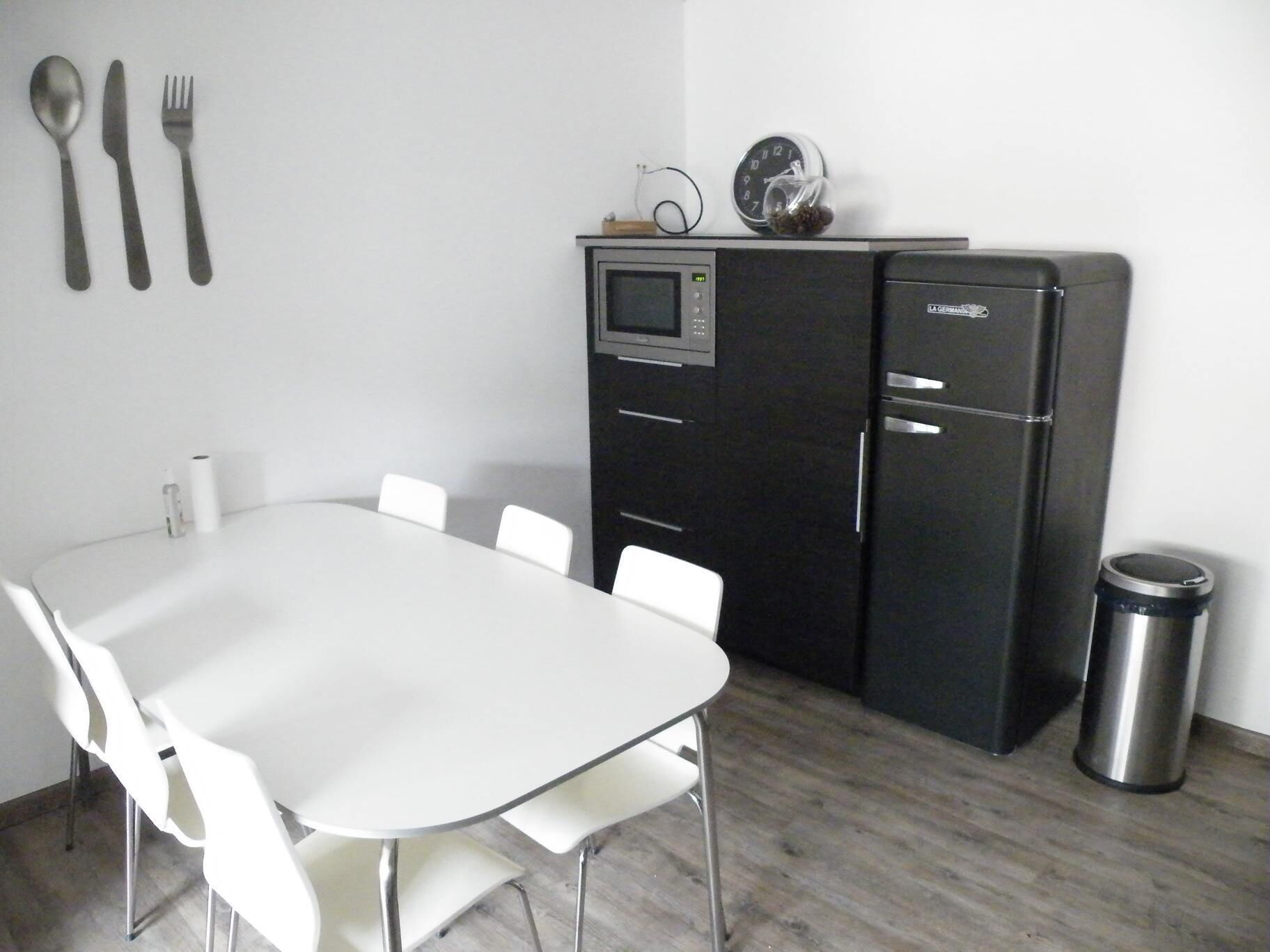 A compact kitchen with a microwave, refrigerator, and a small clock on the wall.
