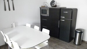 Cocina compacta con microondas, refrigerador y un pequeño reloj en la pared.