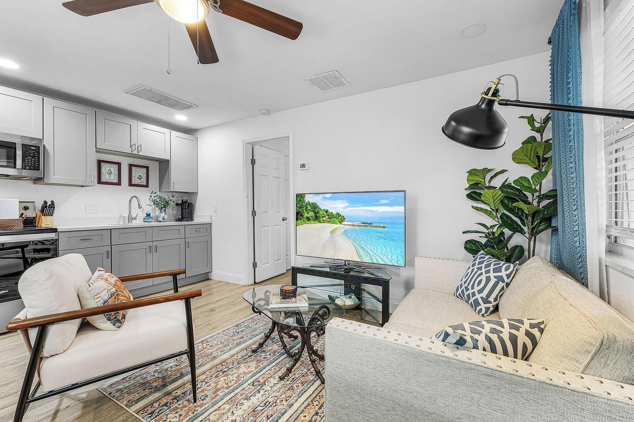 Ein modernes Wohnzimmer mit einer Couch, einem Couchtisch und einem Fernseher, der eine Strandansicht zeigt.