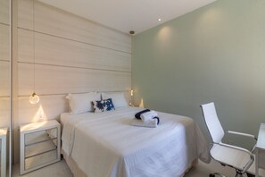 A neatly arranged hotel room with a bed, bedside tables, a chair, and a desk. - Apartment on Gigoia Island Gigoia Class (Rio de Janeiro)