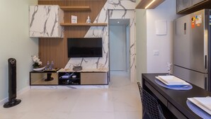A modern kitchen with a built-in TV, marble backsplash, wooden accents, and a refrigerator. - Apartment on Gigoia Island Gigoia Class (Rio de Janeiro)