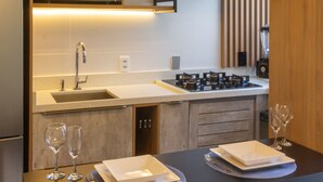 A modern kitchen with a built-in microwave, stainless steel sink, and gas stove. There are two wine glasses and plates on the counter. - Apartment on Gigoia Island Gigoia Class (Rio de Janeiro)