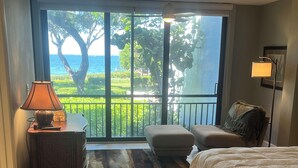 A bedroom with a bed, a nightstand, a lamp, a chair, and a view of the sea through large windows. - Waterfront, Direct View/Access, 2/2 TownHome, Grnd Level w Dock in Key Largo, FL (Key Largo)