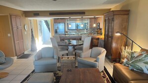 A spacious living room with a wooden coffee table, grey sofas, and a dining area with a glass-top table. - Waterfront, Direct View/Access, 2/2 TownHome, Grnd Level w Dock in Key Largo, FL (Key Largo)