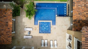 An outdoor swimming pool with a hot tub, lounge chairs, and a staircase leading to a building. - Casa Zafiro 7 Bdrs Private Pool in Los Suenos (Jacó)