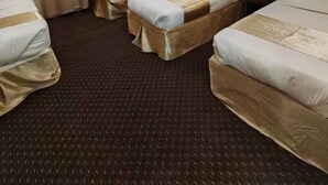 Ein Hotelzimmer mit zwei Einzelbetten, einem großen Fenster mit Vorhängen, einem Teppichboden und einer Deckenleuchte.