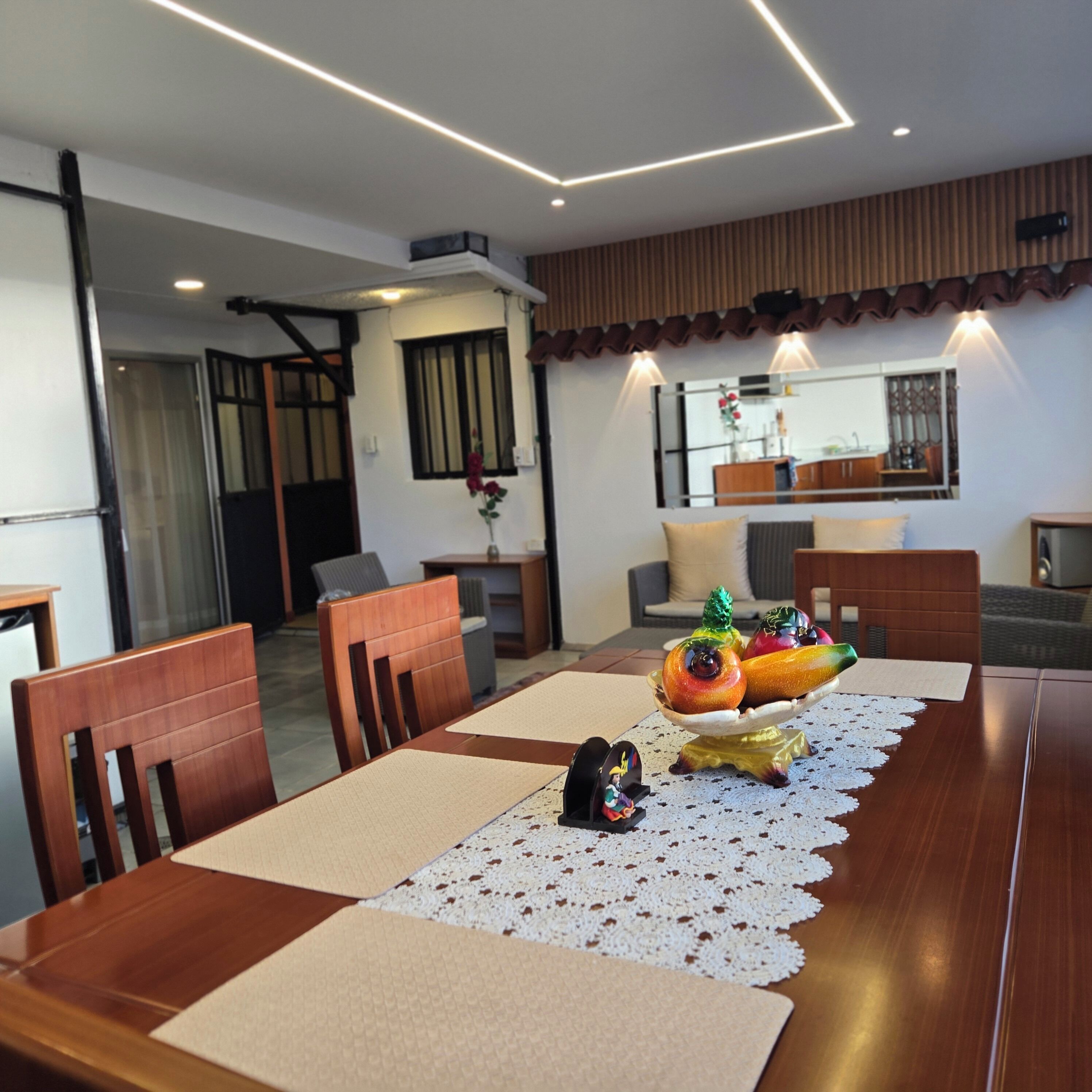 A dining area with a wooden table, chairs, and a fruit centerpiece.