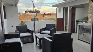 A rooftop patio with wicker furniture, a satellite dish, and a view of buildings in the background. - El Paisaje cuencano, 1 dorm. 2 camas, en el centro historico con una linda vista (Cuenca)
