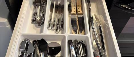 A kitchen drawer with utensils and cookware.