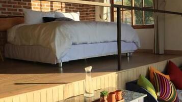 Een slaapkamer met een bed, een raam en een kleine kitchenette.