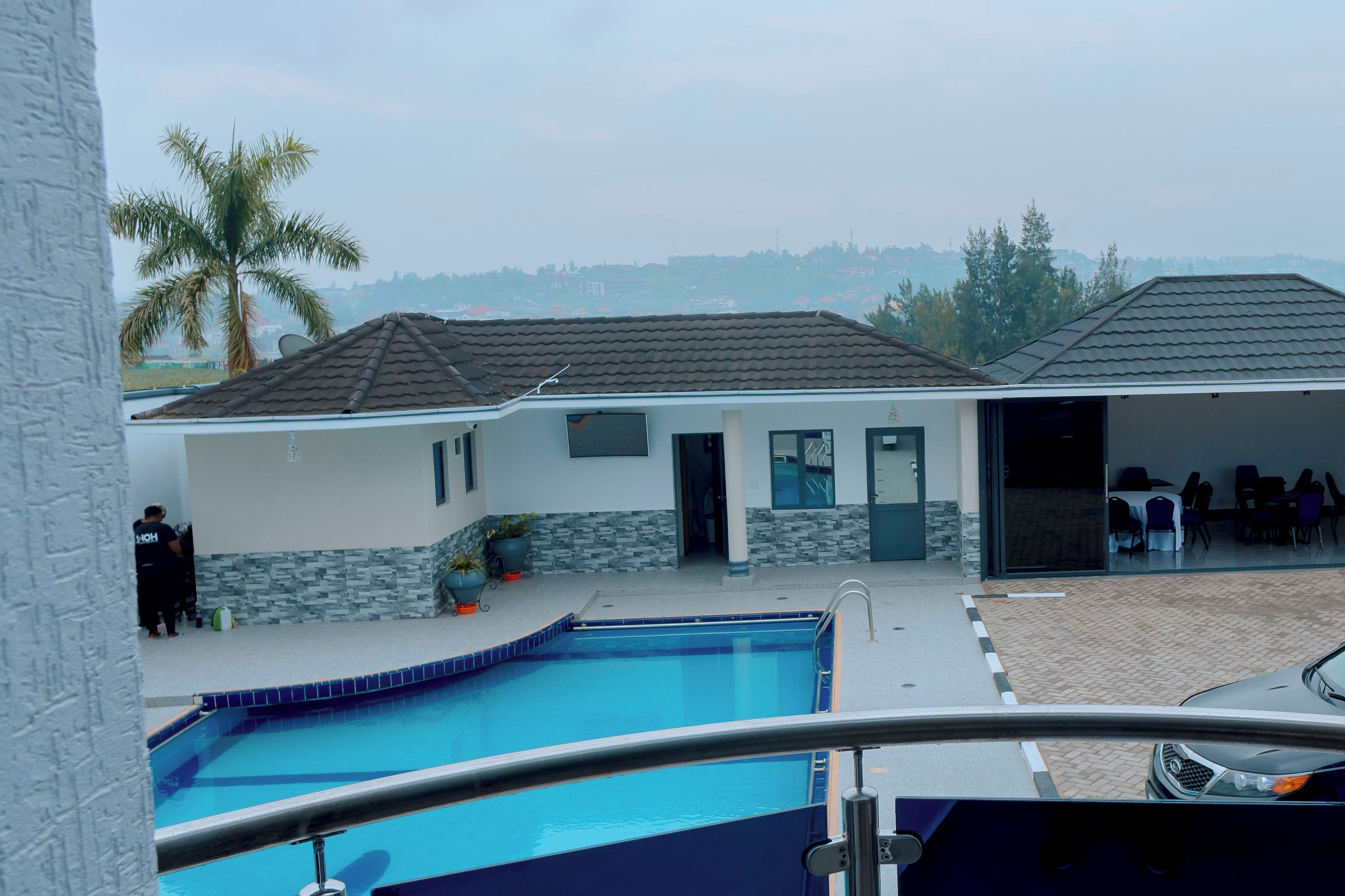 A swimming pool area with a covered patio and a view of a residential neighborhood.