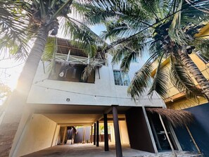 A modern building with a concrete exterior, large windows, and a covered outdoor area with palm trees. - Villa Casa Cocos private for 10 people in Tulum (Tulum)