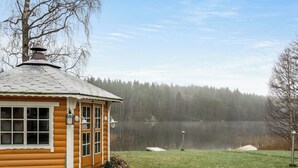 A log cabin with a small porch and a view of a lake surrounded by trees. - Joutsenranta by Interhome (Tuusniemi)
