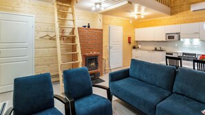 A modern interior with a fireplace, wooden walls, a kitchen, and a blue sofa. - Joutsenranta by Interhome (Tuusniemi)
