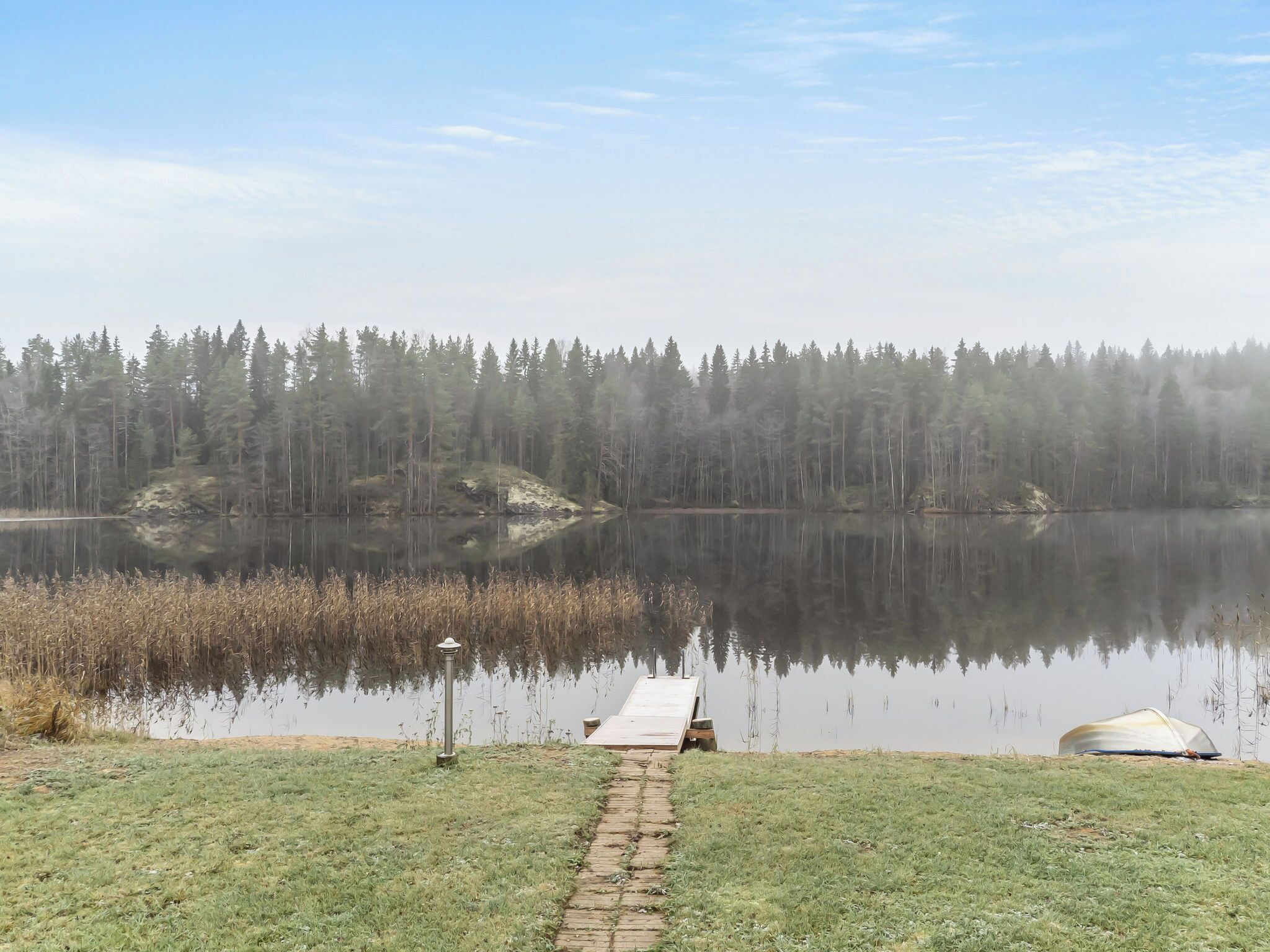 A calm lake with a dock extending into the water, surrounded by dense forest.