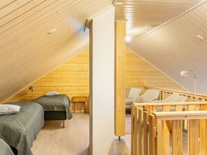 Een knus slaapkamer onder het dak met twee bedden, een houten plafond en een klein bureau.
