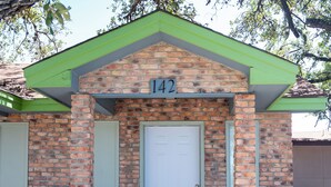 Un petit bâtiment en briques avec un toit vert et une porte blanche.