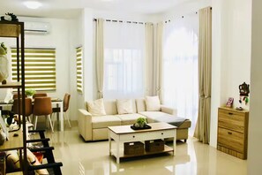 A modern living room with a sofa, coffee table, and dining area.