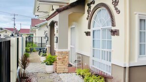 Une maison d’habitation avec une façade en pierre, une entrée sécurisée par un portail et un petit patio agrémenté de plantes en pot.