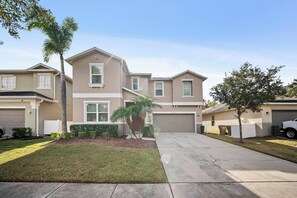 A residential building with a garage, a driveway, and a well-maintained lawn. - 8BR house with private pool in Crystal Cove (Kissimmee)