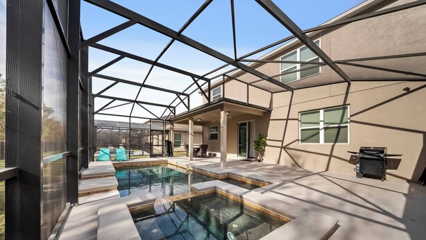 Een modern huis met een serre, een zwembad en een barbecueplek.