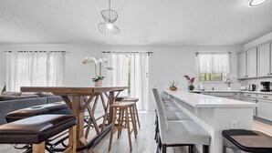 Een moderne keuken met witte kastjes, een houten eiland en een zithoek met een bank en krukken.