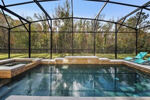 A swimming pool with a glass enclosure, surrounded by a wooden deck and a grassy lawn. - 8BR house with private pool in Crystal Cove (Kissimmee)