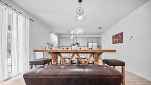 Een moderne keuken met witte kastjes, een houten eettafel en een bruine lederen bank.