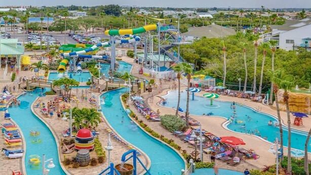 Parque acuático con múltiples piscinas, toboganes y un gran tobogán de agua.
