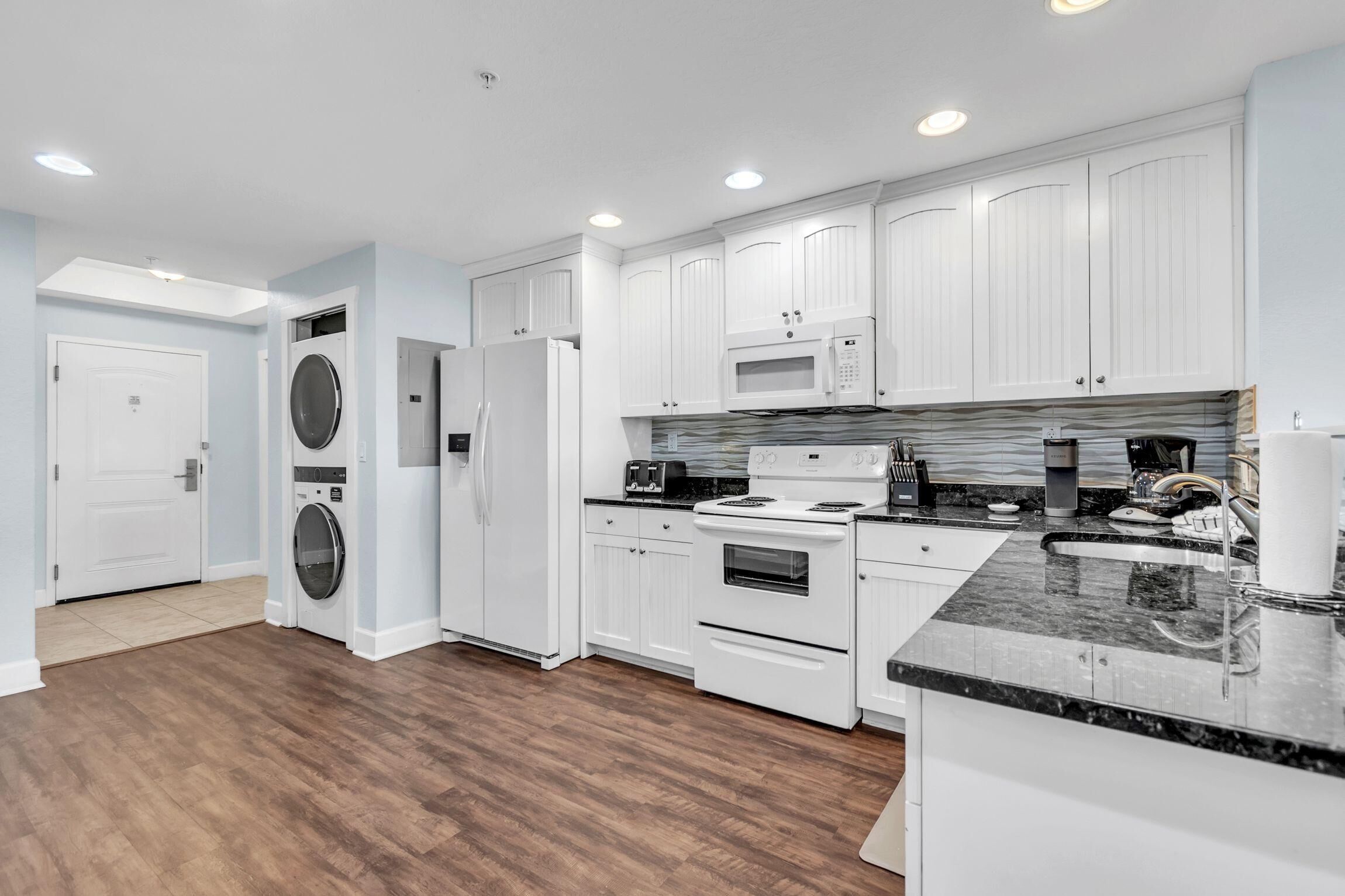 A modern kitchen with white cabinetry, a built-in microwave, a stove, and a large island with a sink.