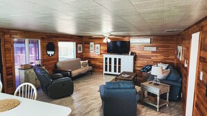 A cozy cabin-style room with a sofa, chairs, a television, and a cabinet.