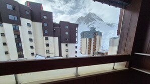 Ein Balkon mit Blick auf einen verschneiten Berg und Gebäude.