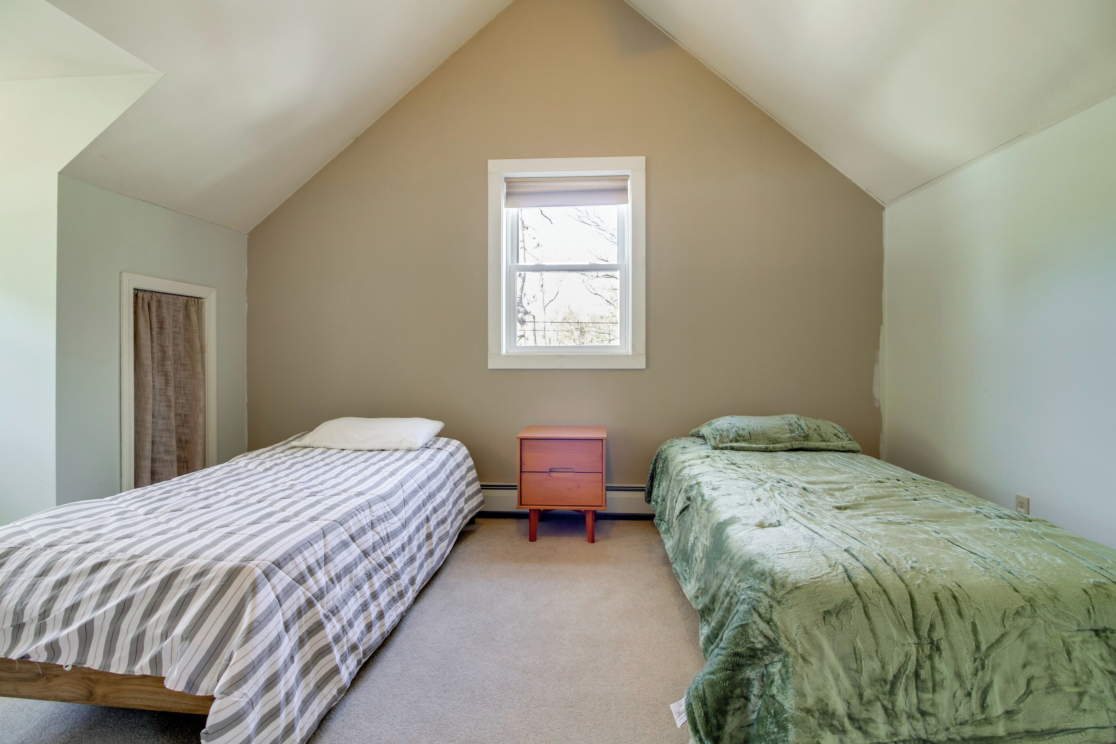 Quarto com duas camas, uma janela e uma mesa de cabeceira.