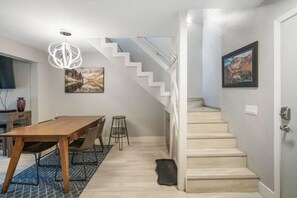 Una cocina moderna con una mesa de comedor de madera, taburetes de bar y una lámpara de araña.